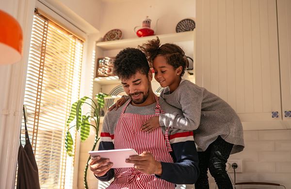 daughter helping father with recipe on tablet daughter helping father with recipe on tablet